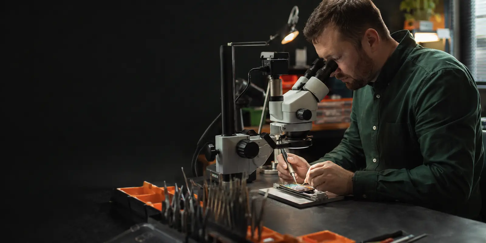 Electronics technician diagnosing a smartphone under a microscope in a professional repair workshop